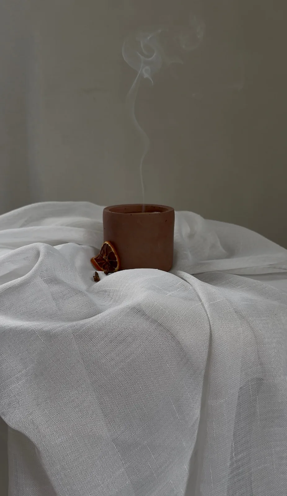 Ember — LUĒR candle with rising smoke beside dried orange and cloves