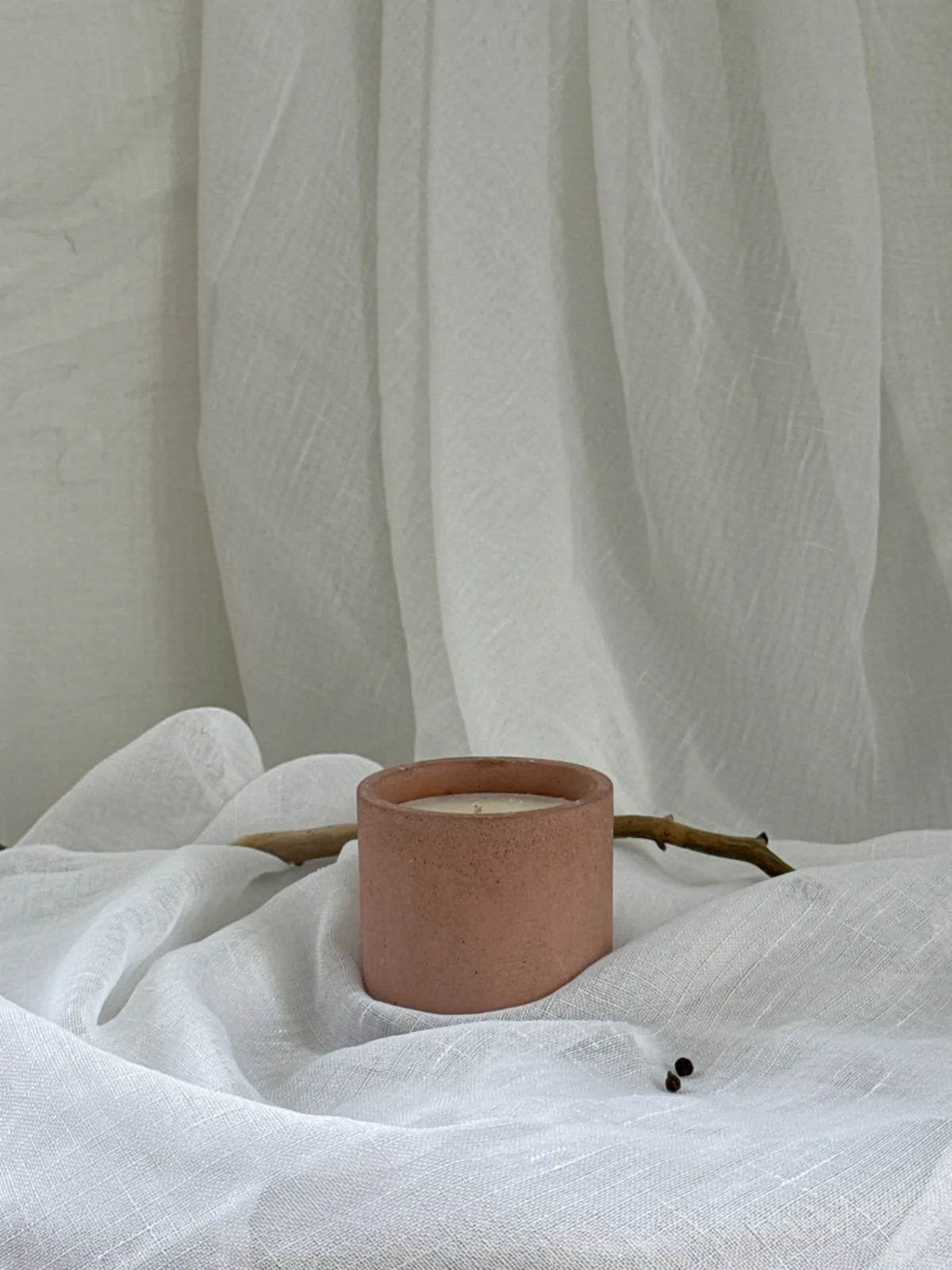 Sol — terracotta LUĒR candle vessel with a branch and peppercorns