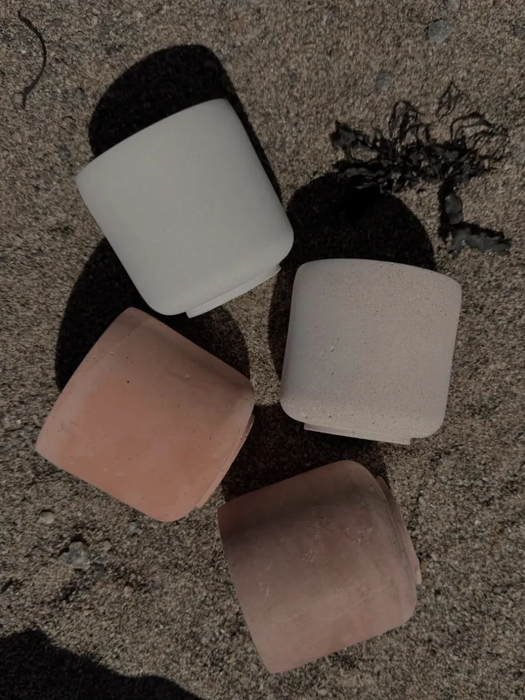 A row of LUĒR candles resting in coastal sand